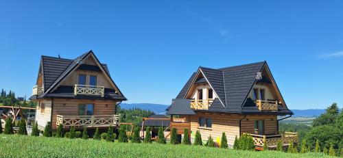 two log homes on a hill with a blue sky at Domki Tatrzański Przystanek in Białka Tatrzanska