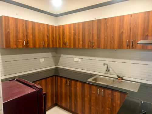 Una cocina con gabinetes de madera y un fregadero. en Kovoor residency, en Thiruvalla