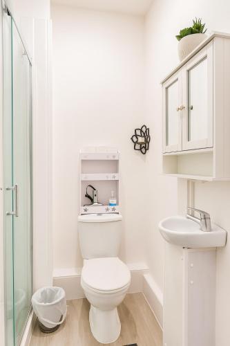 a white bathroom with a toilet and a sink at Shalom Stay London in London