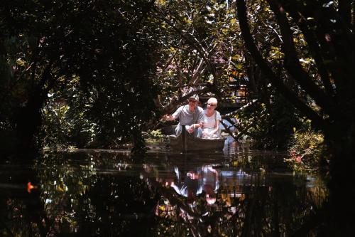 a man and woman sitting in a boat on the water at Coconut Lagoon Kumarakom - A CGH Earth Experience in Kumarakom