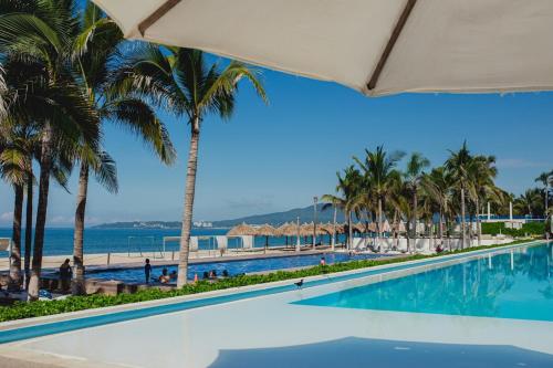 a swimming pool with palm trees and a beach at Ocean view - Studio in front of Nuevo Vallarta beach in Nuevo Vallarta 