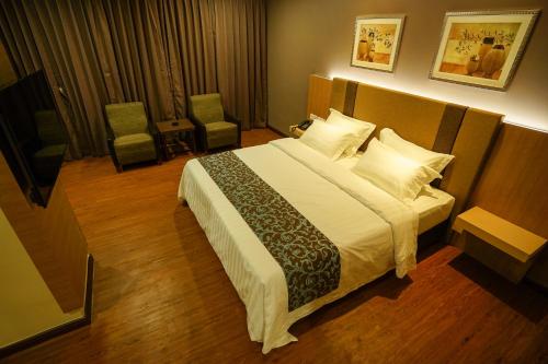 a bedroom with a large bed and two chairs at Hotel Anika Kluang in Kluang