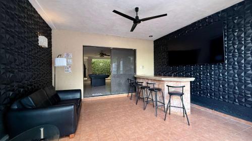 a living room with a bar with stools and a ceiling fan at Alojamiento para 6 personas con piscina in Chuburná de Hidalgo