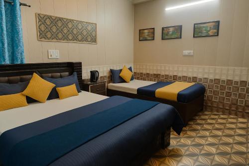 a hotel room with two beds with blue and yellow pillows at Hotel Rajnandani Palace by IQ Hotels - Steps from Ram Mandir, Ayodhya in Ayodhya
