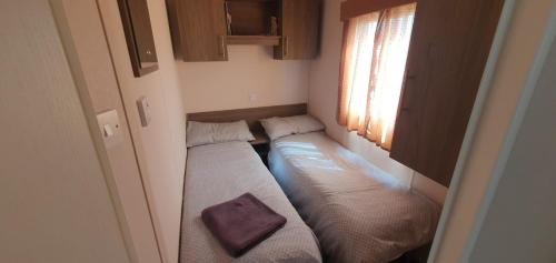 a small room with two beds and a window at Hayling Island Caravan in Hayling Island