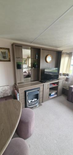 a living room with a fireplace and a tv and a table at Hayling Island Caravan in Hayling Island