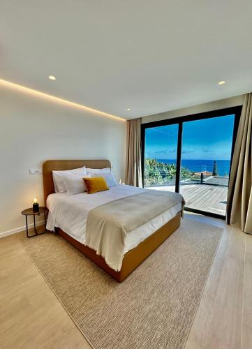 a bedroom with a large bed and a large window at Eco Fajã Villas in Arco da Calheta