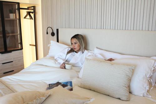 a woman sitting in bed with a cup of coffee at LUUM by Norus in Santiago