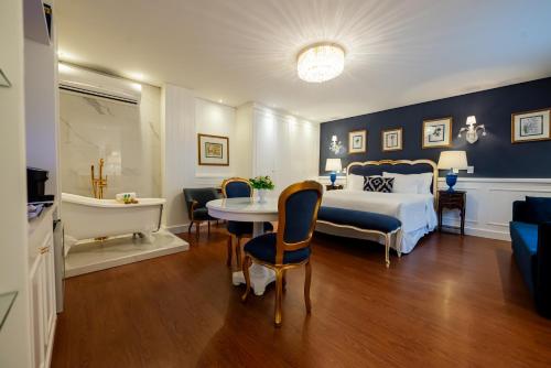 a bedroom with a bed and a table and a tub at Villa do Vale Boutique Hotel in Blumenau