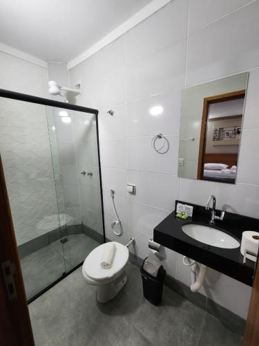 a bathroom with a shower and a toilet and a sink at Hotel Villa Real in Piratininga