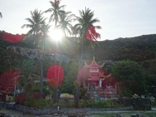 a temple with palm trees in front of a mountain at Cham Island Smiles Homestay in Tân Hiệp