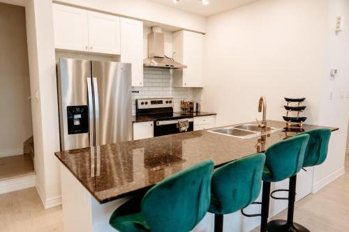 a kitchen with a counter with green bar stools at Luxury 2-Bed Townhouse Near Waterfront & Downtown in Ajax