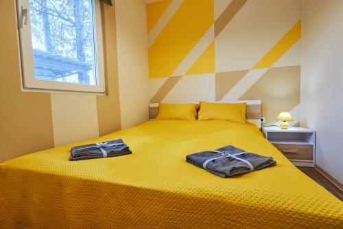 two towels on a yellow bed in a bedroom at Bodza apartman 1 - Sarud in Sarud