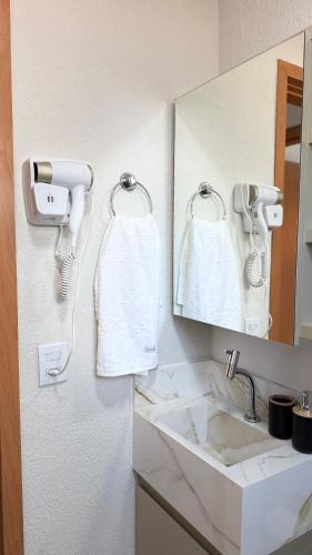 a bathroom with a sink and a mirror and towels at Refúgio de Luxo in Montes Claros