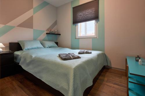 a bedroom with a bed with a green comforter and a window at Bodza apartman 1 - Sarud in Sarud