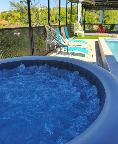 a hot tub filled with blue water next to a pool at Agava Club in Sremska Kamenica