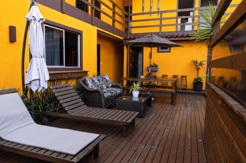 an outdoor deck with chairs and an umbrella and a table at Pousada Maria Eduarda in Guarda do Embaú