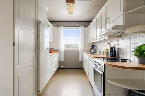 a kitchen with white cabinets and a window at Tomasjord home, the top floor in Trondalen