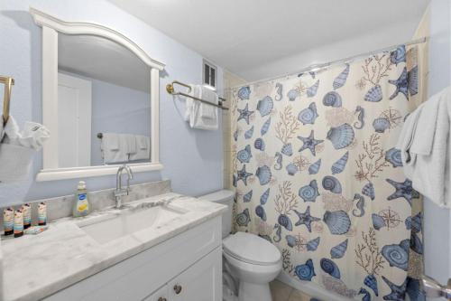 a bathroom with a sink and a toilet and a mirror at Renovated 2-Bedroom Condo with Pool - The Waves in St. Pete Beach