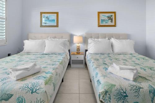 a bedroom with two beds and a lamp on a table at Renovated 2-Bedroom Condo with Pool - The Waves in St. Pete Beach