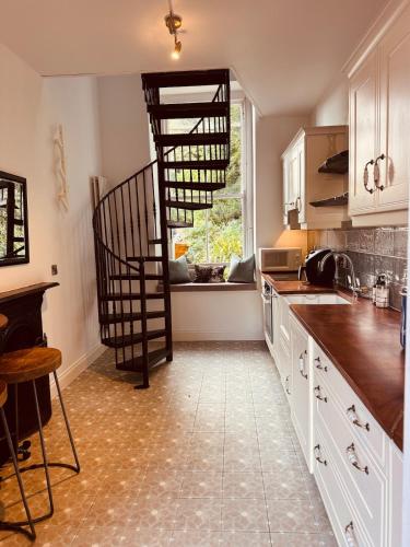 a kitchen with a spiral staircase in a kitchen at The Arches, Georgian Apartment in Cobh