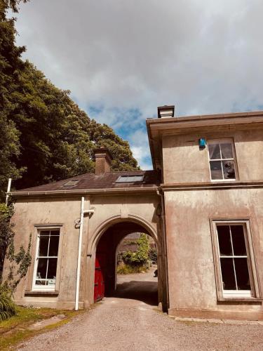 an old building with an archway with a red door at The Arches, Georgian Apartment in Cobh