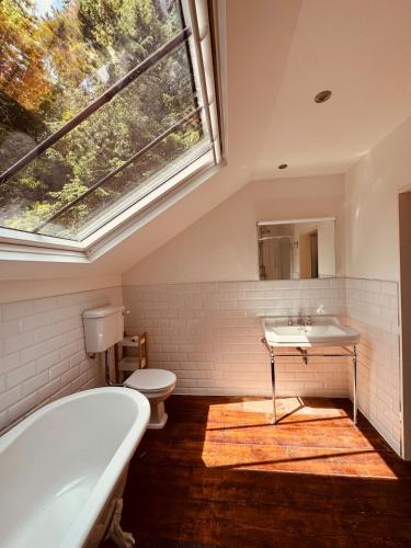 a bathroom with a tub and a sink and a window at The Arches, Georgian Apartment in Cobh