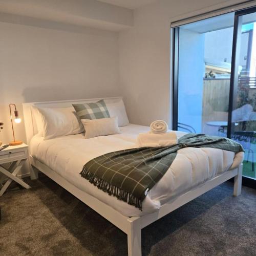 a white bed in a room with a window at Central Christchurch Studio - Allen Street in Linwood