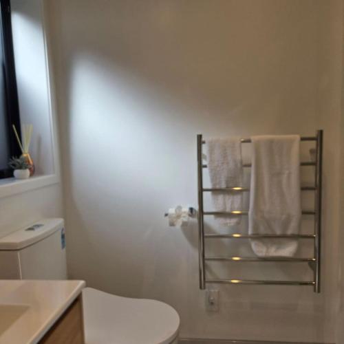 a bathroom with a toilet and towels on a towel rack at Central Christchurch Studio - Allen Street in Linwood