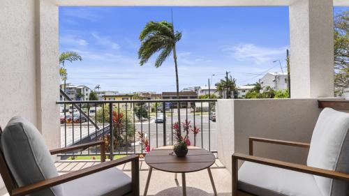 Un balcón con sillas, una mesa y una palmera en Urban Getaway on Grafton, en Cairns