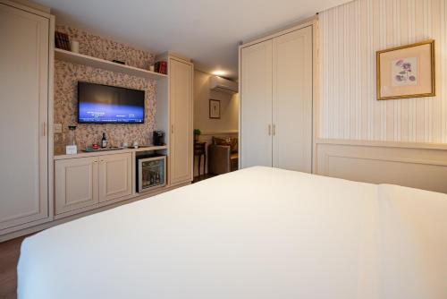a bedroom with a bed and a flat screen tv at Villa do Vale Boutique Hotel in Blumenau