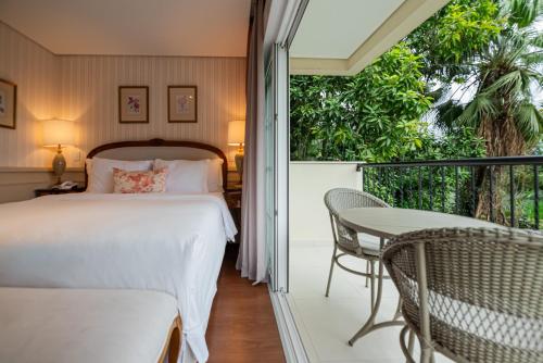 a bedroom with a bed and a balcony with a table at Villa do Vale Boutique Hotel in Blumenau