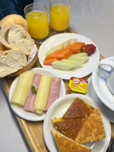 a wooden table with plates of food and glasses of orange juice at Status Elegance Hotel in Serra