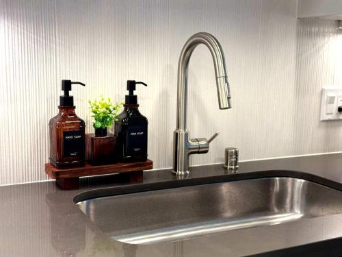 a kitchen sink with two bottles of soap at Bright Condo 10 Min from Disneyland With Pool & GYM in Tustin