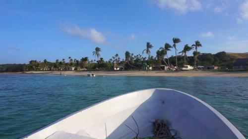 a boat in the water next to a beach at Yasawa Homestays in Nacula Island