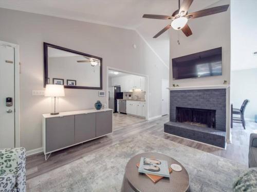 a living room with a fireplace and a ceiling fan at Cozy 3BR Bungalow - City Views - Firepit -Football in Charlotte