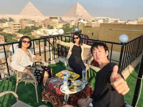 a group of people sitting on a balcony with pyramids at Eyad Pyramids view in Cairo