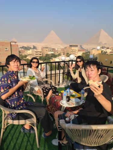 a group of people sitting on a balcony eating food at Eyad Pyramids view in Cairo