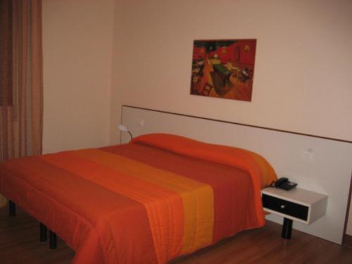 a bedroom with a bed with an orange blanket at Hotel Ristorante Klaus in Porto Tolle