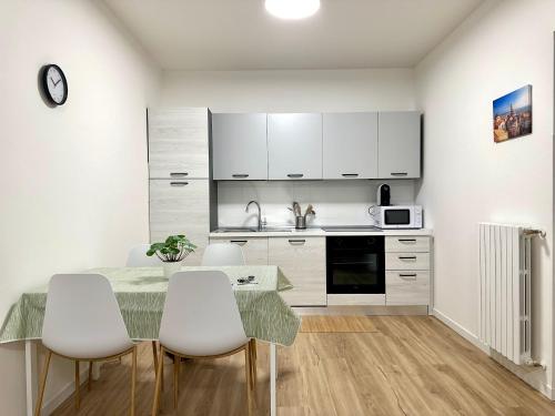 a kitchen with white cabinets and a table and chairs at Fly&Stay Bergamo Airport in Zanica