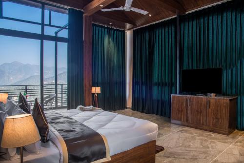 a bedroom with a bed and a tv and a large window at The BlackPearl Hillcrest in Kasauli