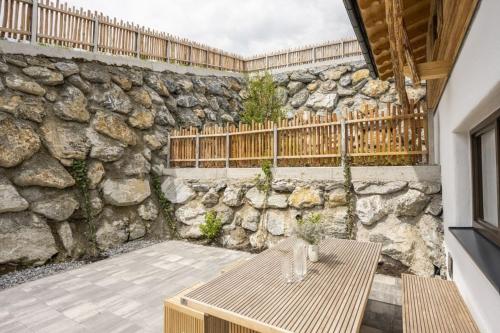 a patio with a stone wall and a wooden table at AAF - Comfort Chalet Bergzeit in Forstau