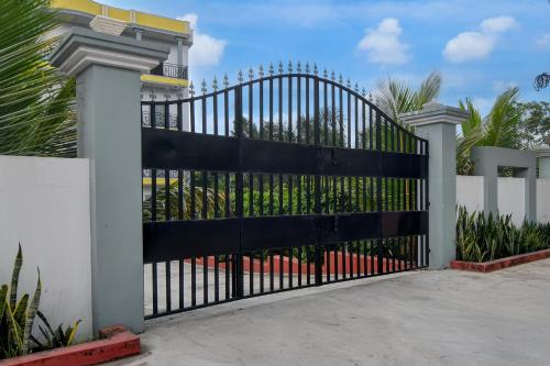 a black metal gate in front of a white fence at SPOT ON The Green Palace in Lālbāgh