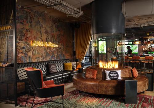a lobby with a leather couch and a bar at Moxy Louisville Downtown in Louisville