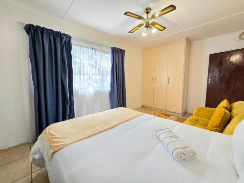 una camera da letto con un grande letto bianco e un ventilatore a soffitto di Coastal Retreat a East London