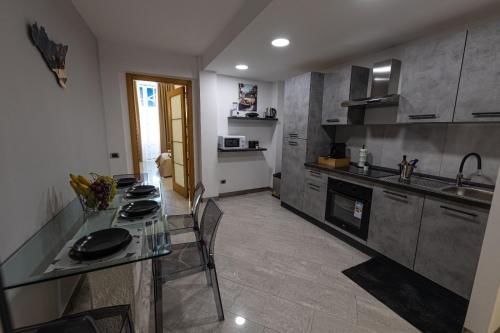 una cucina con tavolo in vetro e piano di lavoro di Fiera & Luna appartament a Catania