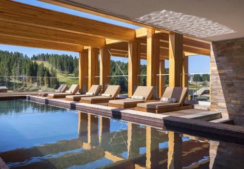a row of lounge chairs next to a swimming pool at Viceroy Kopaonik Serbia in Kopaonik