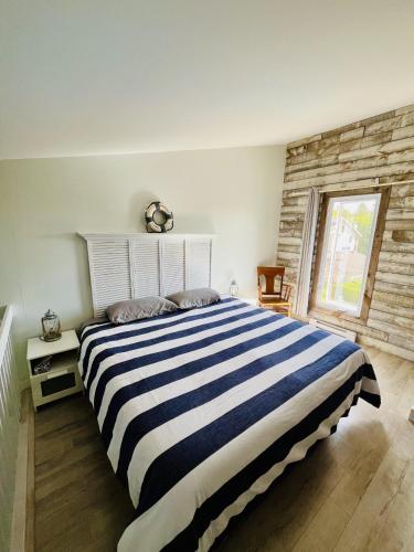 a bedroom with a large bed with a striped blanket at Lumineux condo au bord du lac in Magog-Orford