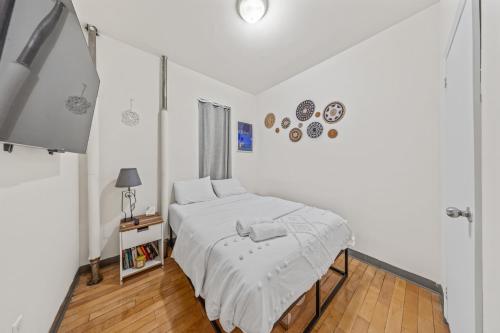 a white bedroom with a bed and a window at Heart of Downtown Manhattan - Stylish One Bedroom Apartment in Vibrant Union Square in New York