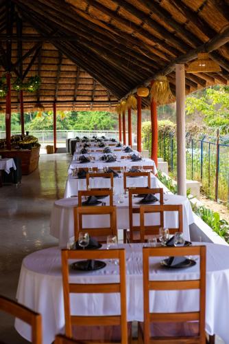 a long row of tables with white tablecloths at Resort Açude 